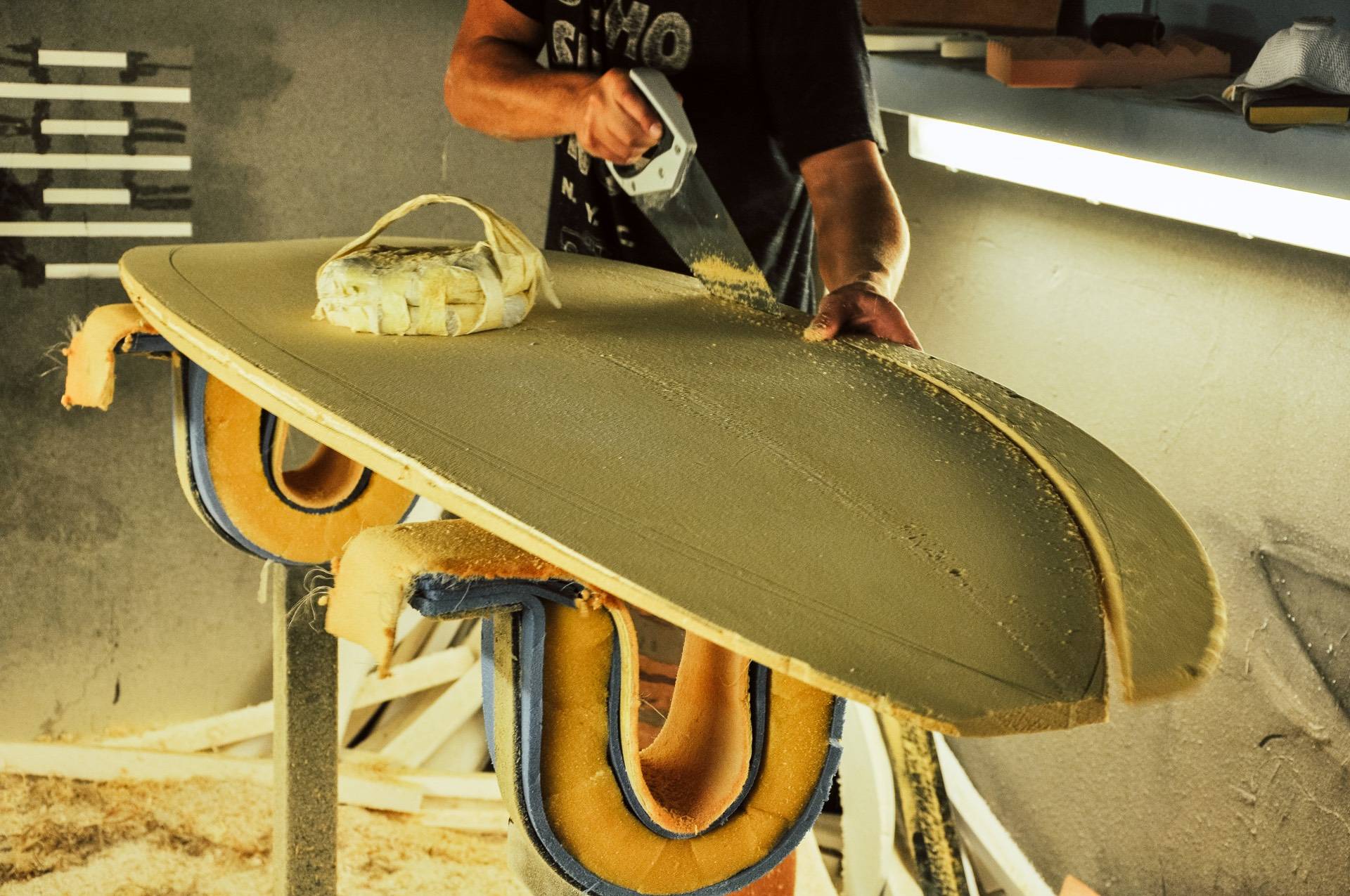 Un shaper découpe une planche de surf en matériau recyclé.